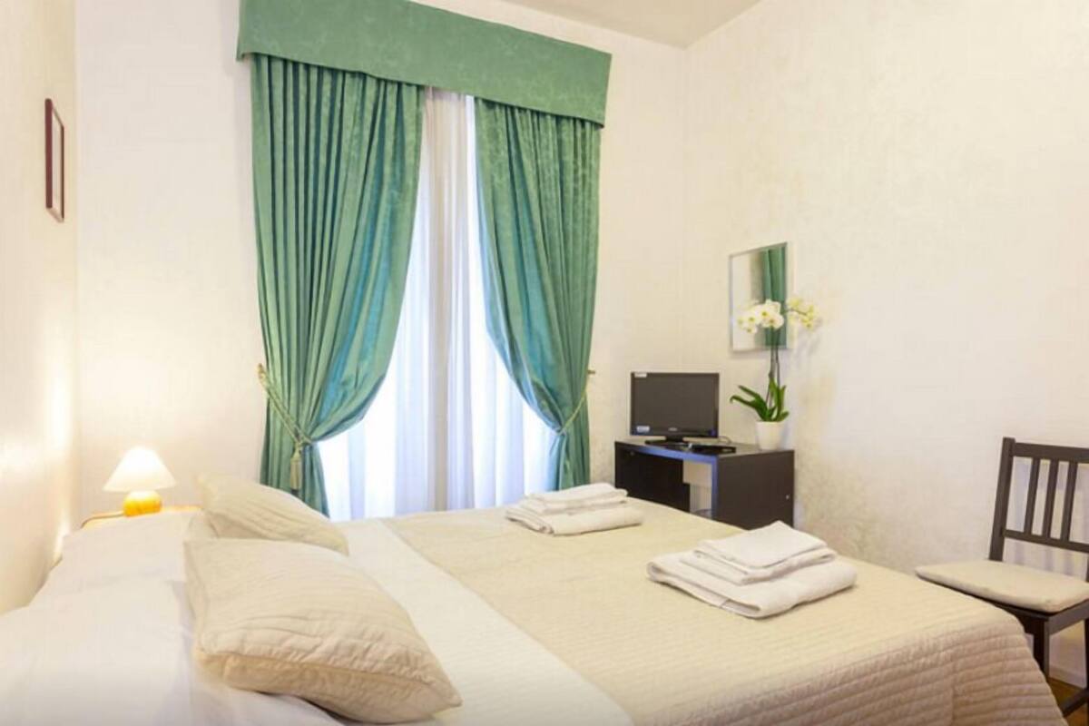 A hotel room with two beds, a desk with a computer, a chair, and a TV.