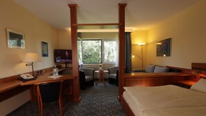Una habitación de hotel con cama, escritorio, sillas y televisor.