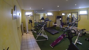 Un gimnasio con diversos equipos de ejercicio, incluyendo cintas de correr, elípticas y máquinas de pesas.