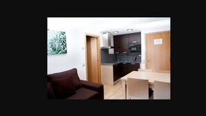 Een compacte leefruimte met een kitchenette, een eethoek en een bank.
