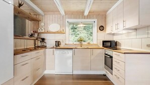 A modern kitchen with wooden cabinets, a dishwasher, a microwave, and a window with a view of trees. - Awesome home in Hovborg with WiFi (Hovborg)