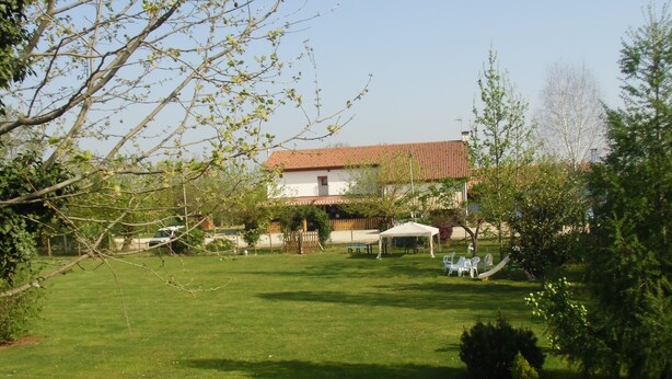 A grassy yard with a white building, a fenced area, and a tent. - Podere Vedelago (Vedelago)