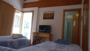 A bedroom with two beds, a TV, wooden beams, a painting, and a door. - Podere Vedelago (Vedelago)