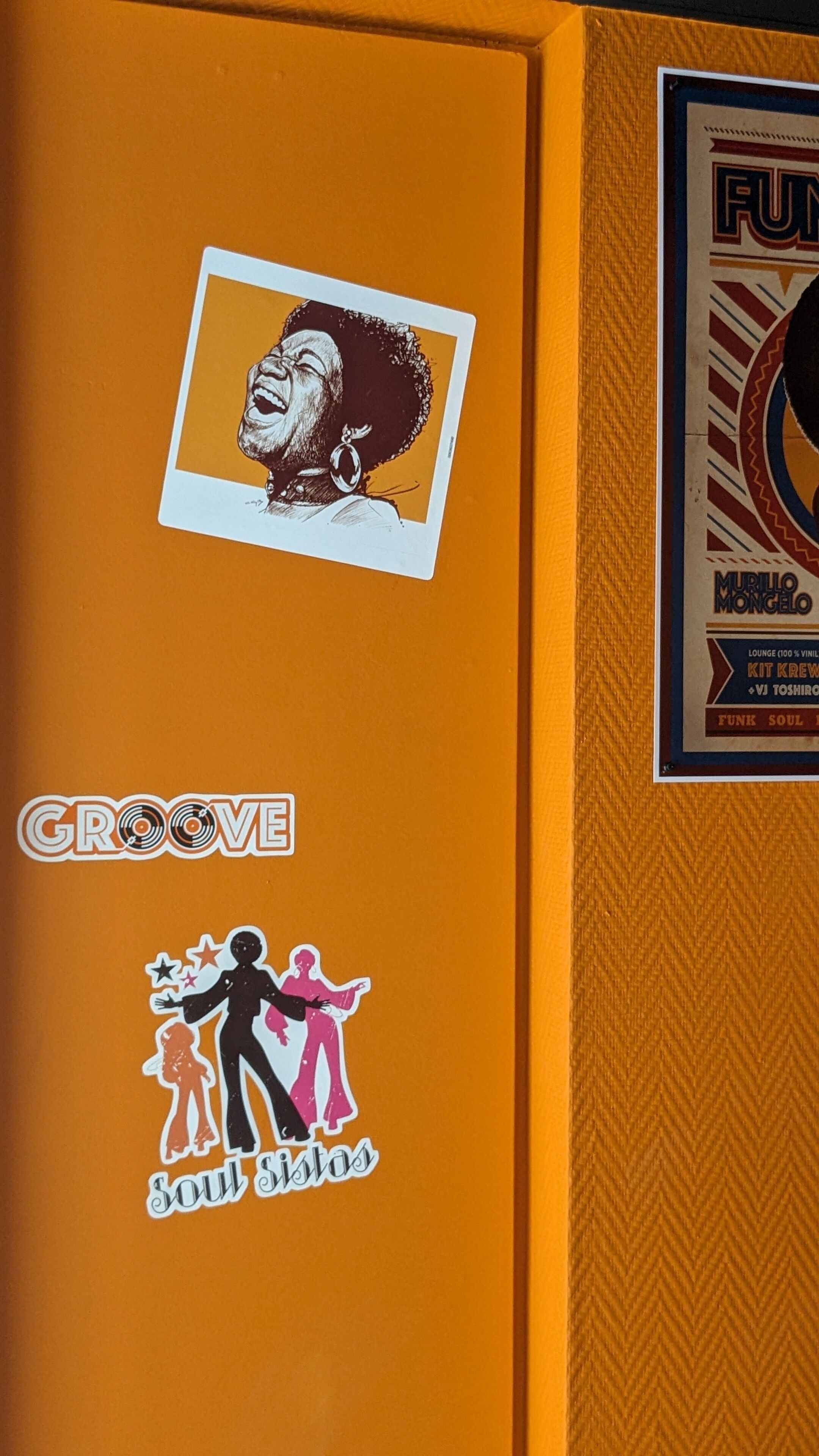 Un mur orné d’un grand panneau orange et d’une affiche encadrée.