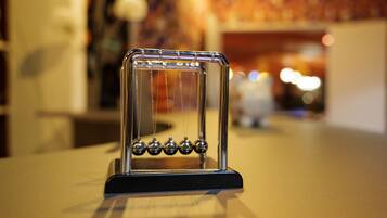 Ein Newtonsches Pendel mit schwarzem Fundament, auf einer reflektierenden Oberfläche platziert.
