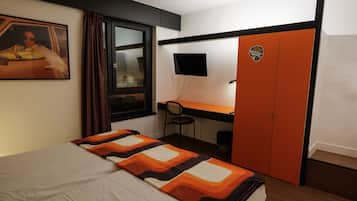 Un dormitorio con cama, escritorio, silla, televisor y armario.