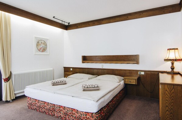 Ein Doppelbett mit Blumendekor, ein hölzernes Kopfteil, ein Nachttisch mit Lampe und ein gerahmtes Bild an der Wand.