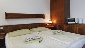 A hotel room with two beds, a wooden headboard, a bedside table with a lamp, a microwave, and a coffee maker. - Pension Baranek (Kaprun)