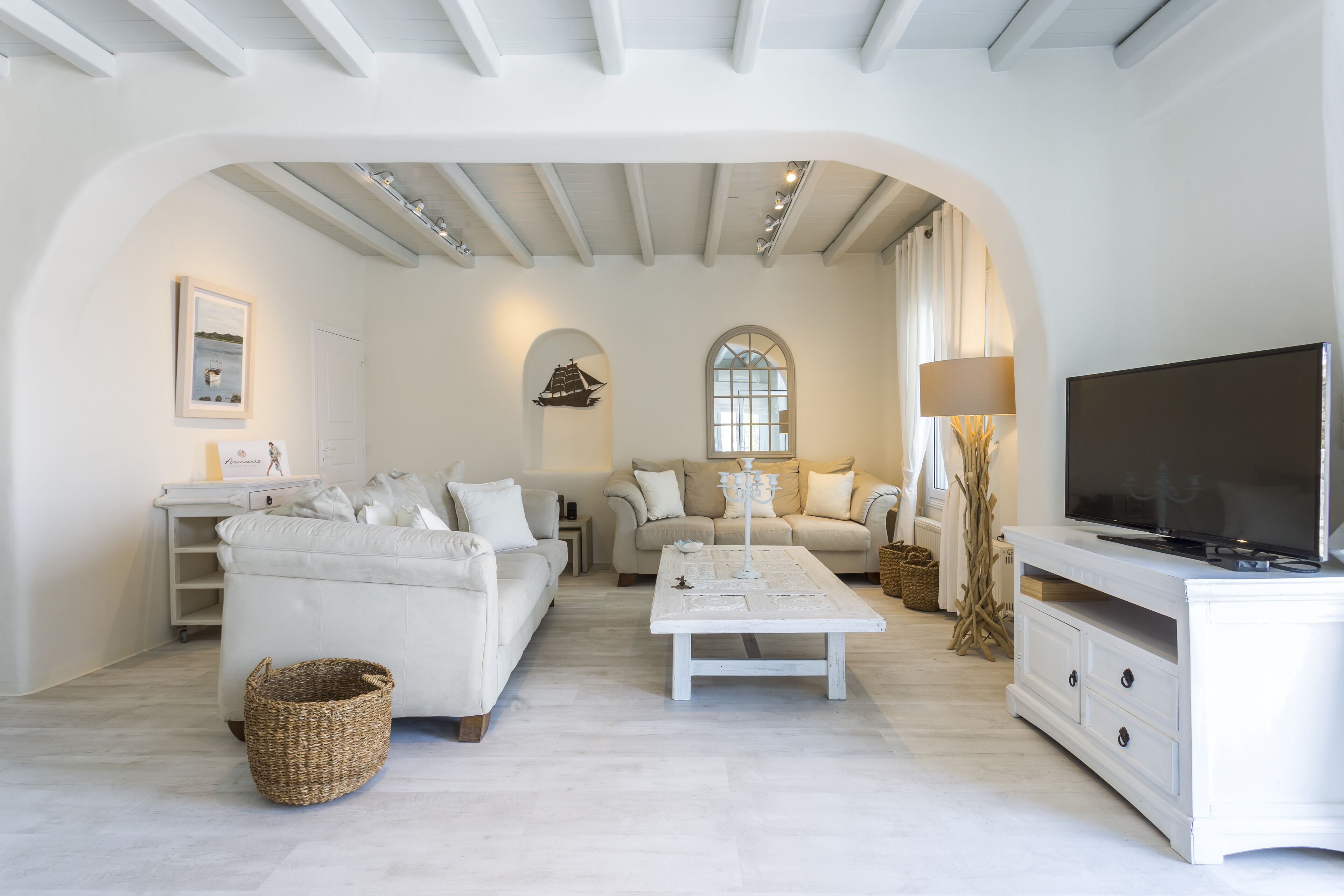 A spacious living room with a white sofa, a coffee table, and a TV stand.