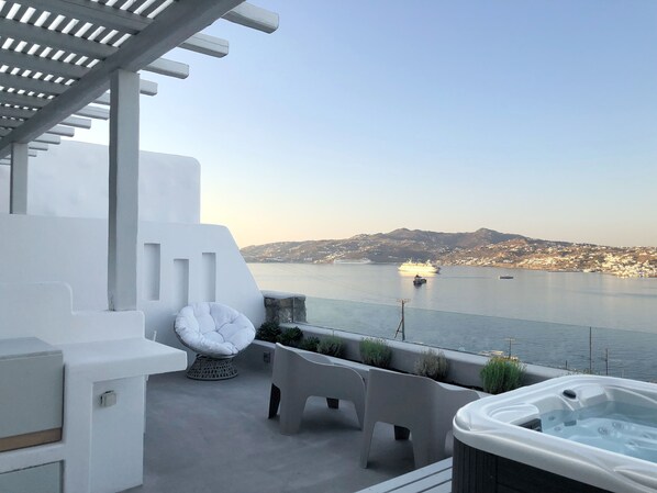 A modern outdoor seating area with a view of the sea and a distant mountain range. - Amaris Mykonian Residence (Mykonos)