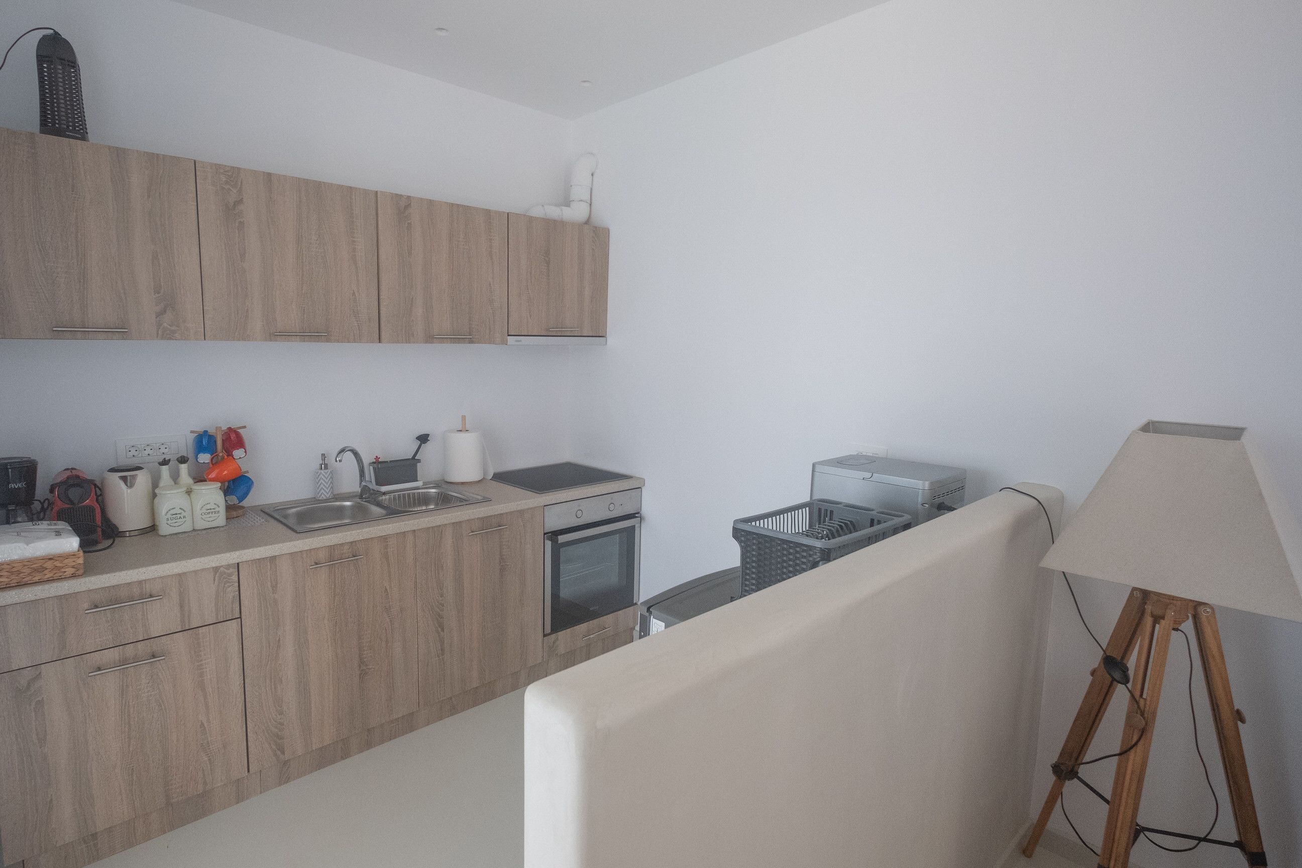 A modern kitchen with wooden cabinets, a sink, a stove, and a small refrigerator.