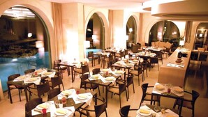 Un restaurante con varias mesas dispuestas para comer, con vista a una piscina.