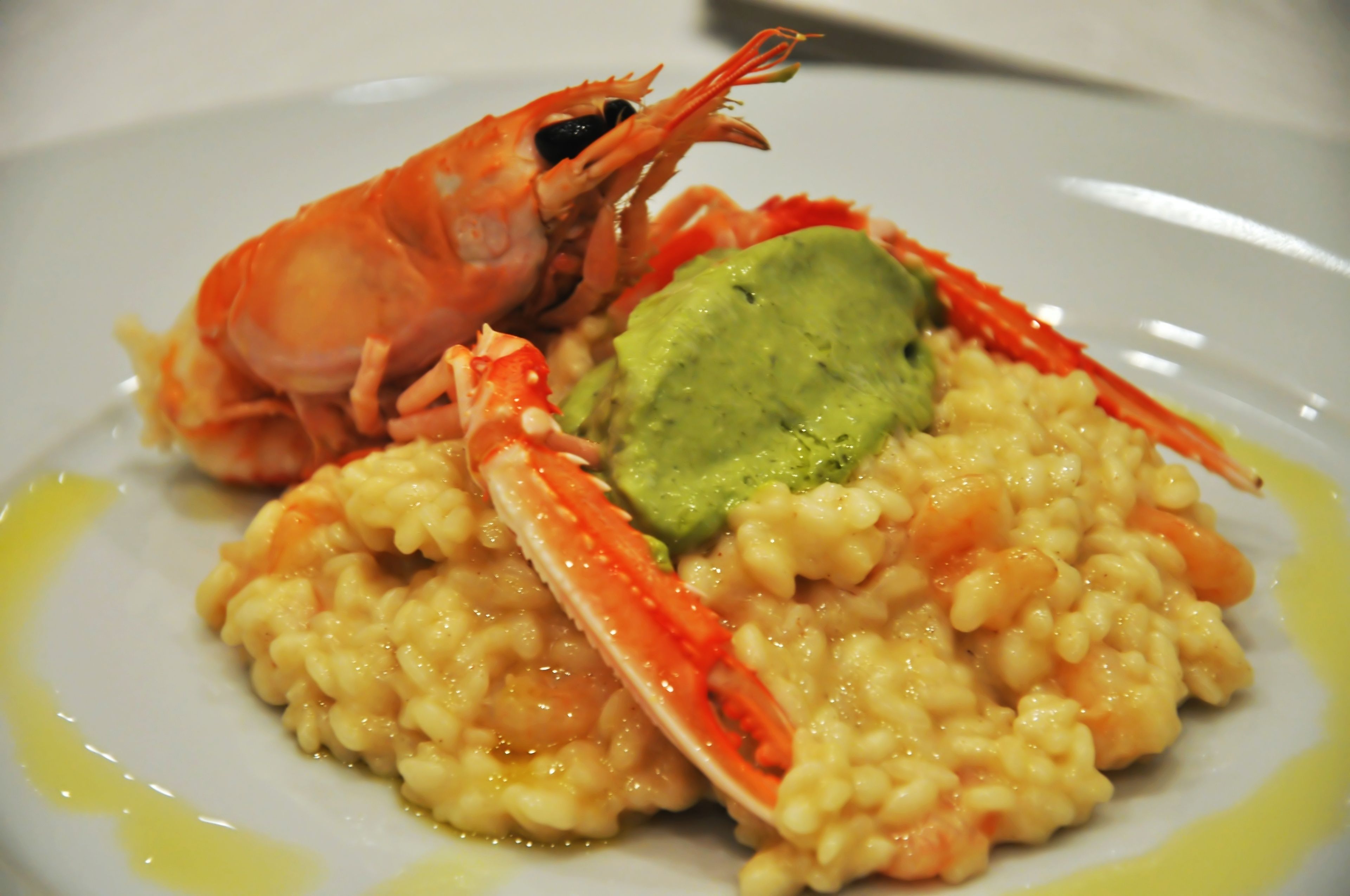 Une assiette de risotto aux crevettes, garnie d’une cuillère de purée d’avocat.