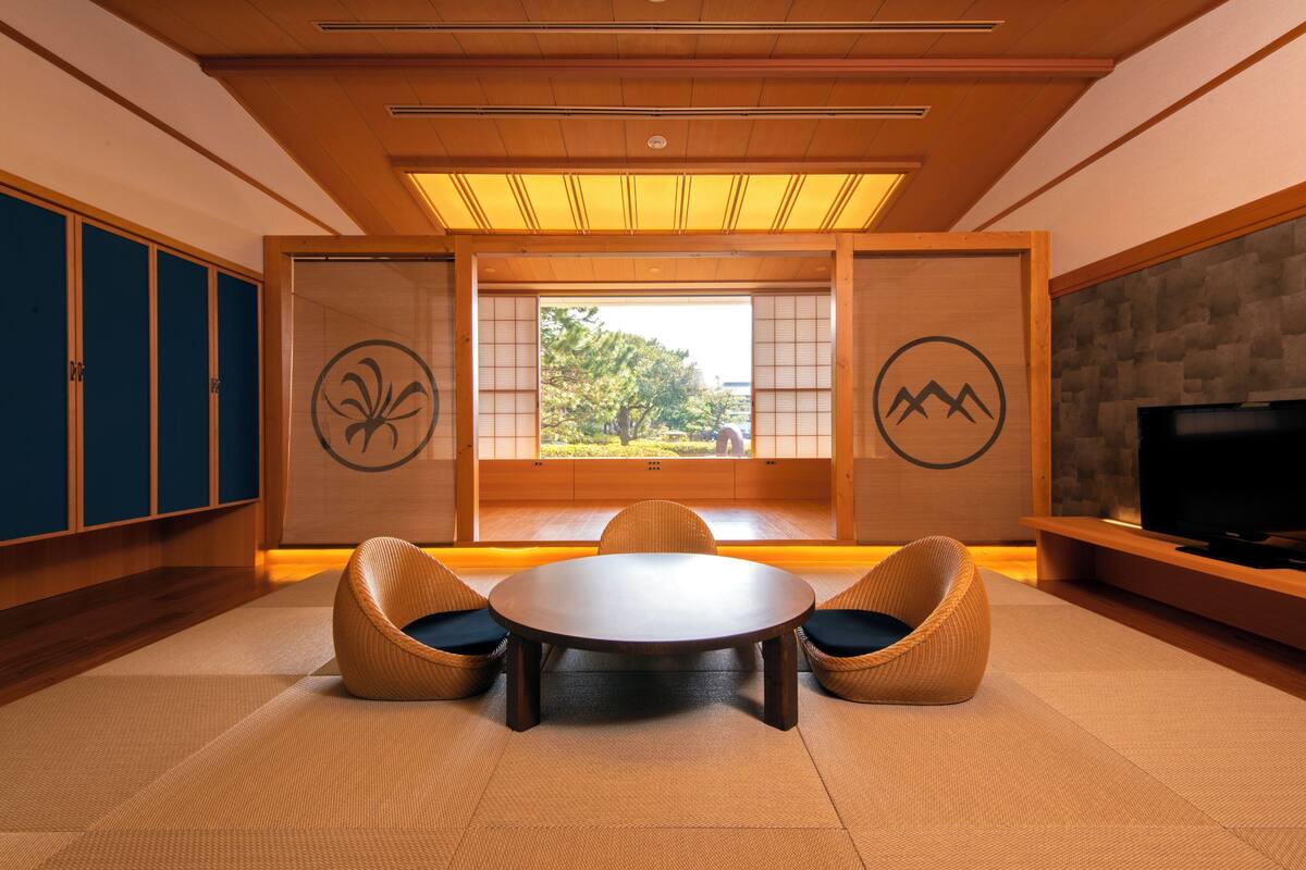Una habitación japonesa tradicional con suelo de tatami, una mesa baja y dos sillas tejidas.
