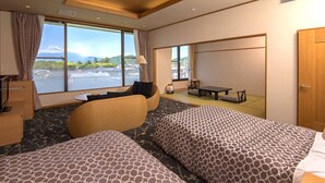 Ein Hotelzimmer mit zwei Betten, einer Couch, einem Tisch und Blick auf einen Berg.