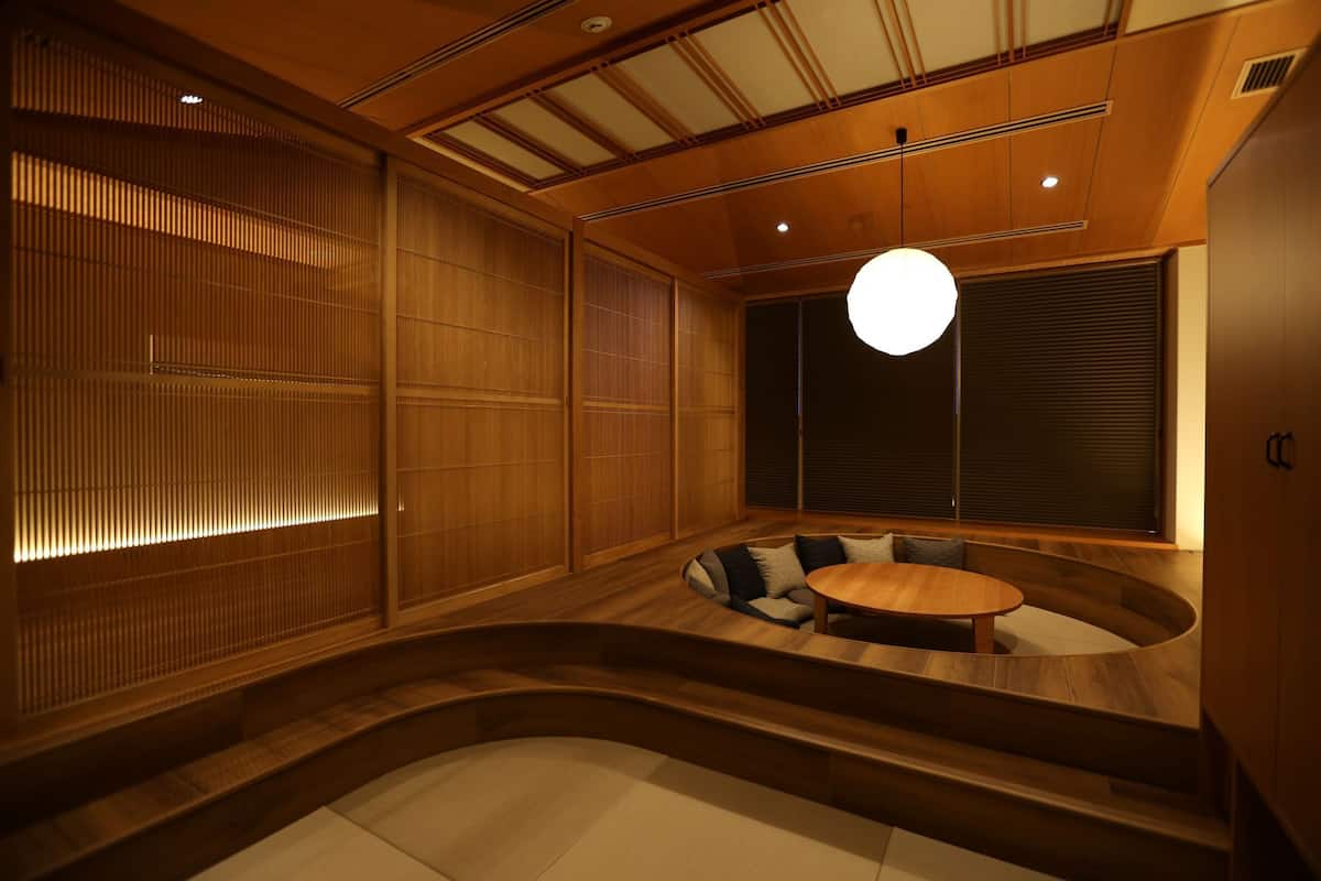 Un interior japonés tradicional con suelo de tatami, una mesa de madera redonda y puertas correderas shoji.