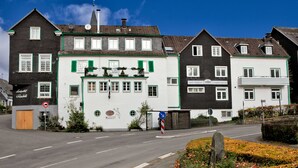 Een rij traditionele gebouwen in Europese stijl, met verschillende architectonische details, waaronder een centraal gebouw met een balkon en een bordje dat een restaurant aangeeft.