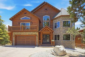 A two-story log cabin with a stone facade, a garage, and a balcony.