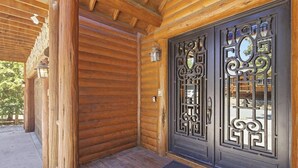 A wooden cabin with a porch, a metal door with intricate designs, and a lantern. - Luxury! 3 Master Suites! Located Near the Lake! Pool Table! Propane BBQ! (Big Bear City)