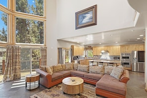 A spacious living area with a large sectional sofa, a kitchen with wooden cabinets, and a dining area.