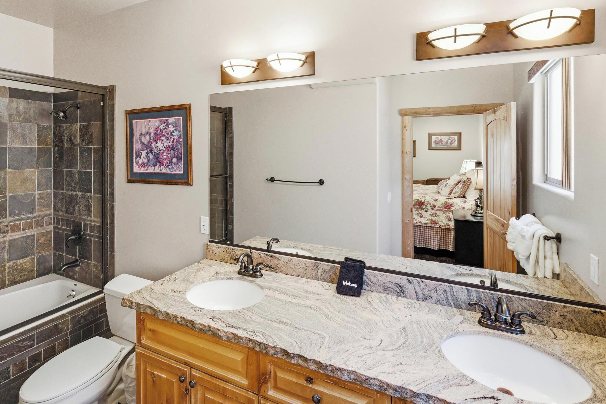 Une salle de bain avec un double vasque, un grand miroir, une douche et des toilettes.