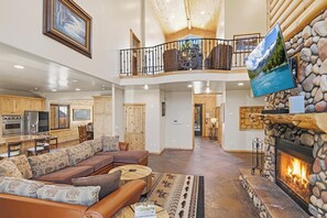 A spacious living area with a fireplace, a dining area, and a kitchen. - Luxury! 3 Master Suites! Located Near the Lake! Pool Table! Propane BBQ! (Big Bear City)