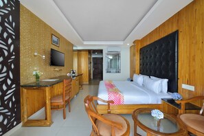 Ein Hotelzimmer mit Bett, Schreibtisch, Stuhl, Fernseher und einem durchgegangenen Tür sichtbaren Badezimmer.