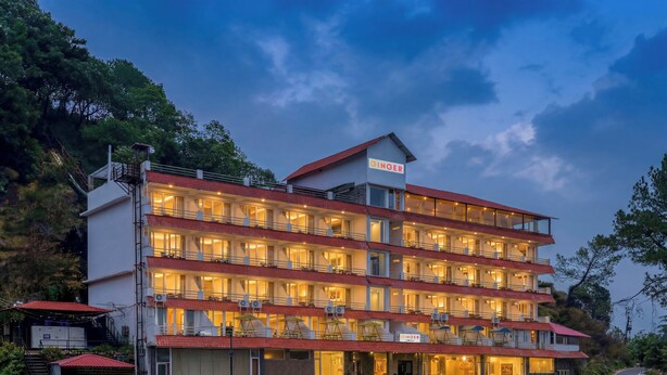 Um hotel de vários andares com telhado vermelho, varandas e uma placa com a inscrição 'GINGER'.