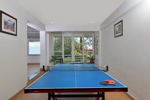 A room with a ping pong table, chairs, and a view through a glass door. - Ginger Lansdowne, Mall Road (Lansdowne)