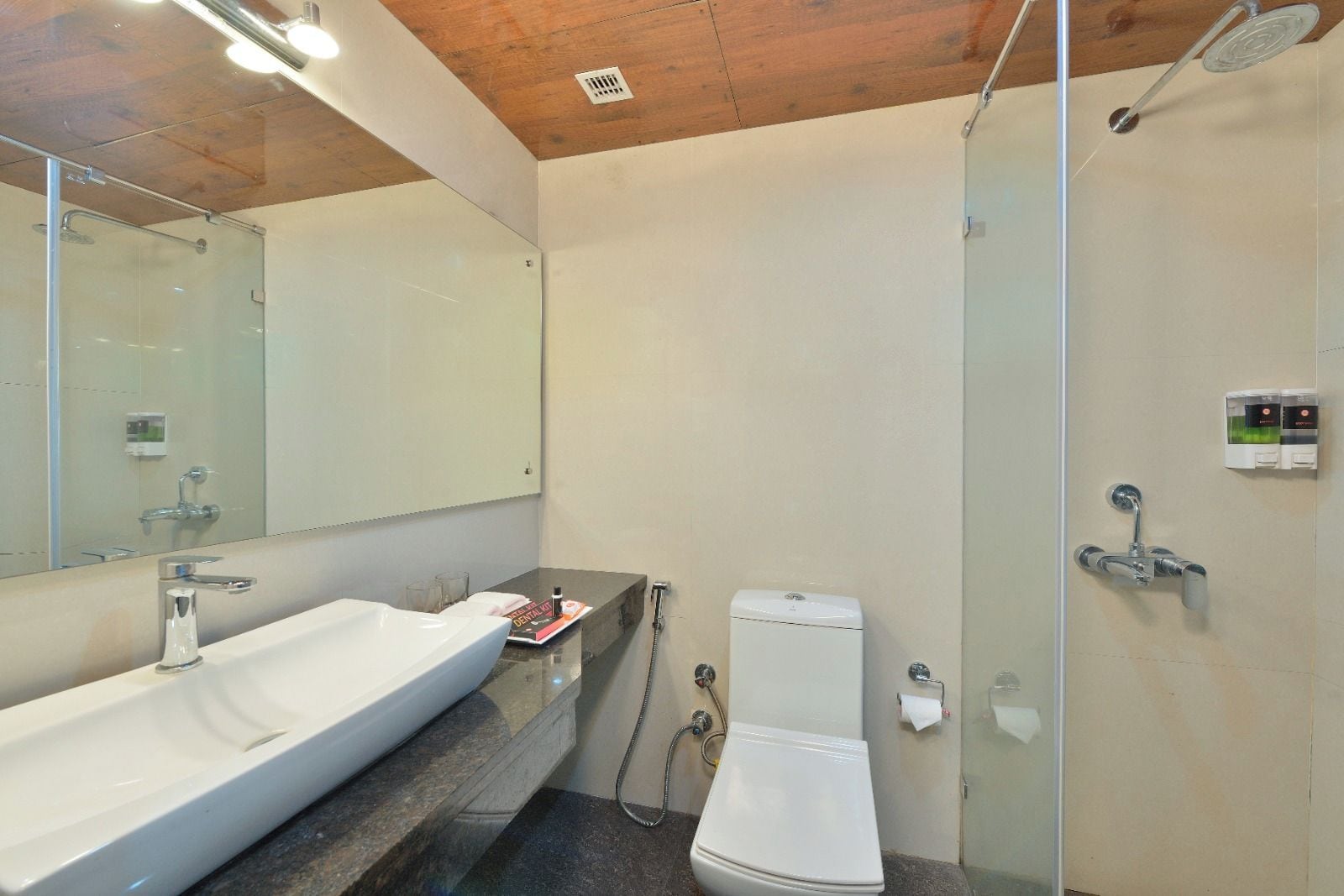 A modern bathroom with a large sink, mirror, toilet, and shower.