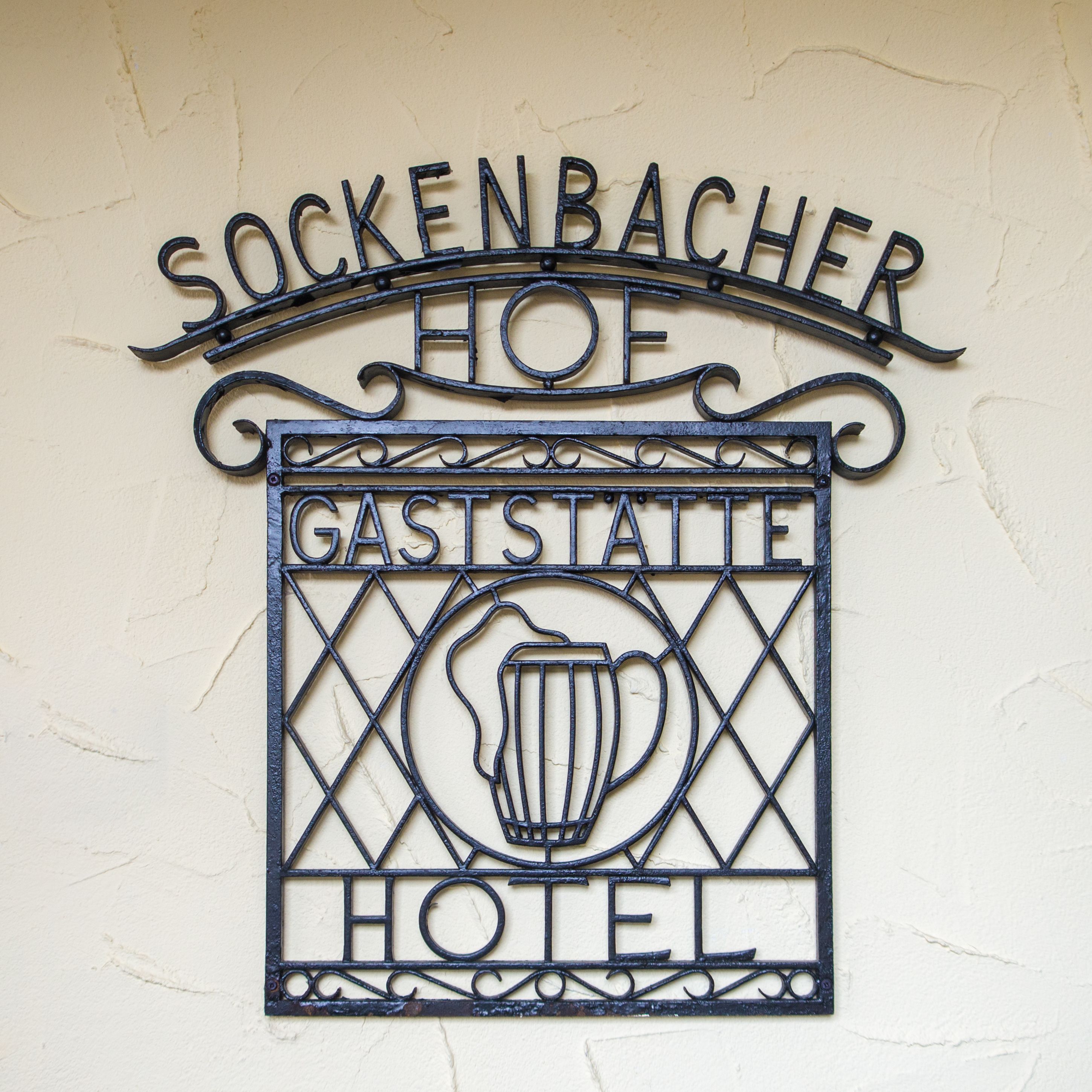 Ein Metallschild mit dem Schriftzug "SOCKENBACHER HOE GASTSTAEL HOTEL" und einer Bierkrug-Ikone.