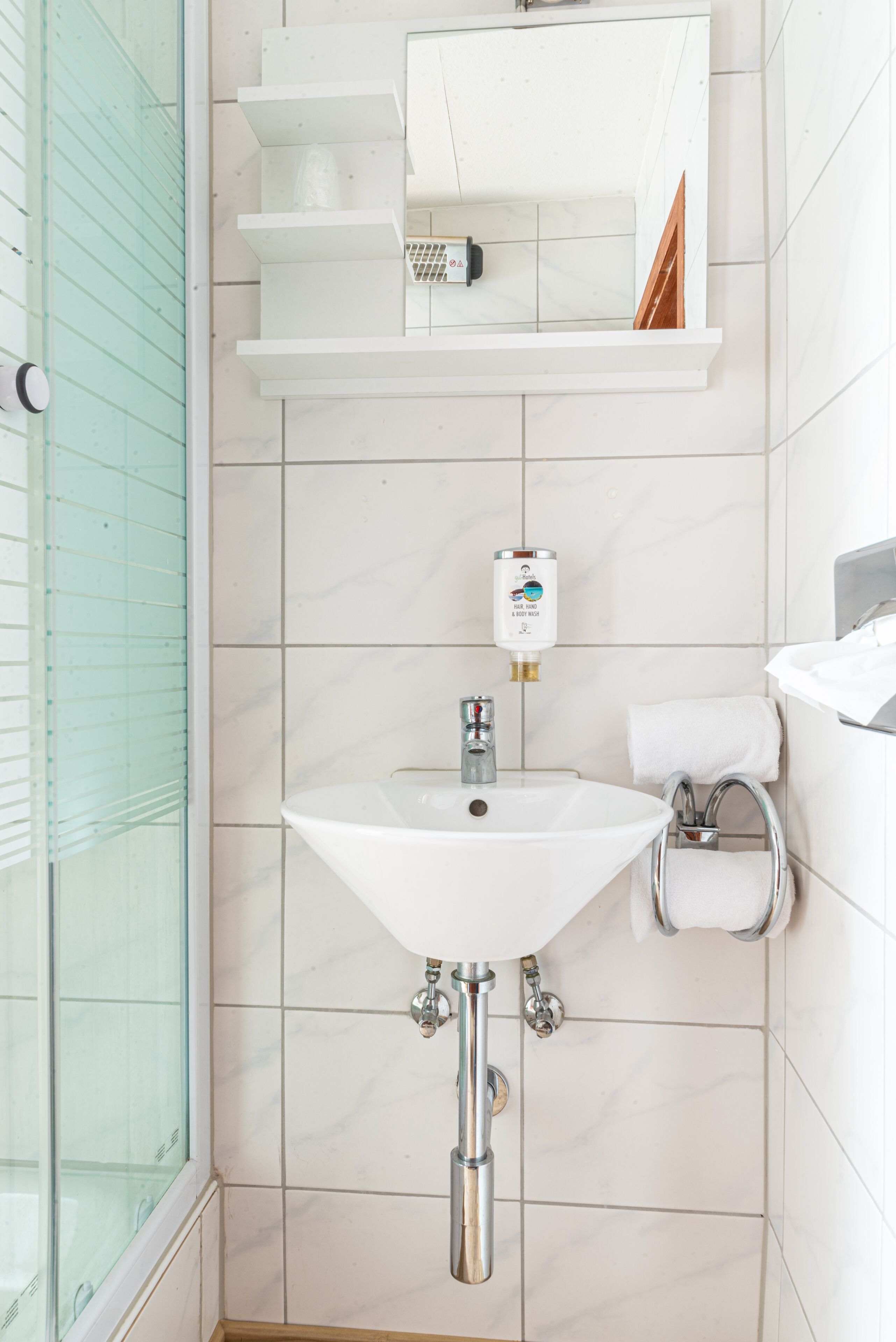 A bathroom with a white sink, a mirror above it, and a glass shower enclosure.