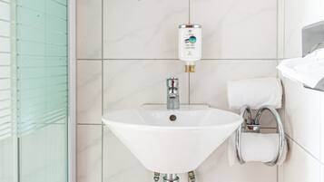 Un baño con un lavamanos blanco, un espejo encima y una cabina de ducha de vidrio.