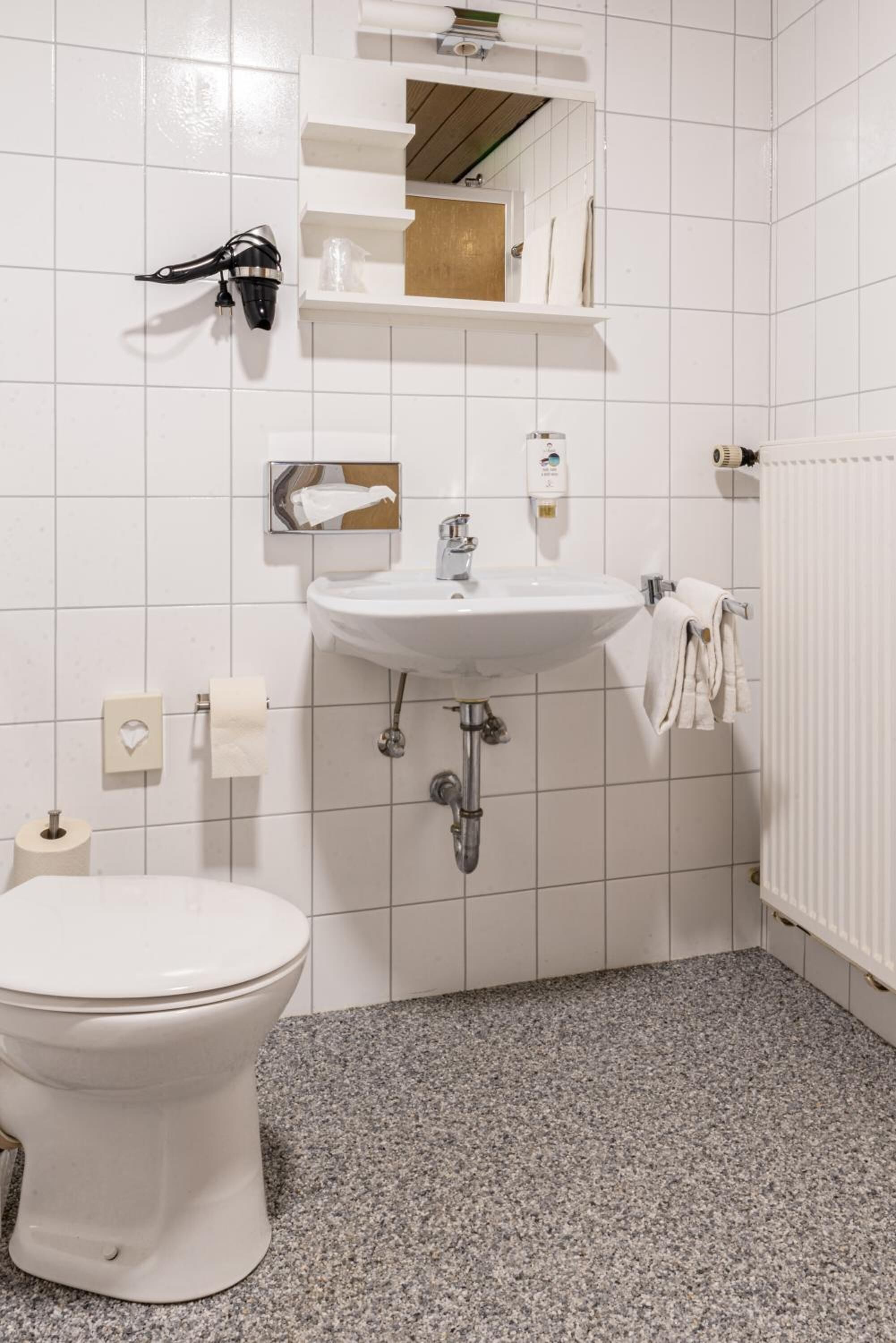 A bathroom with a white toilet, a sink, and a towel rack.