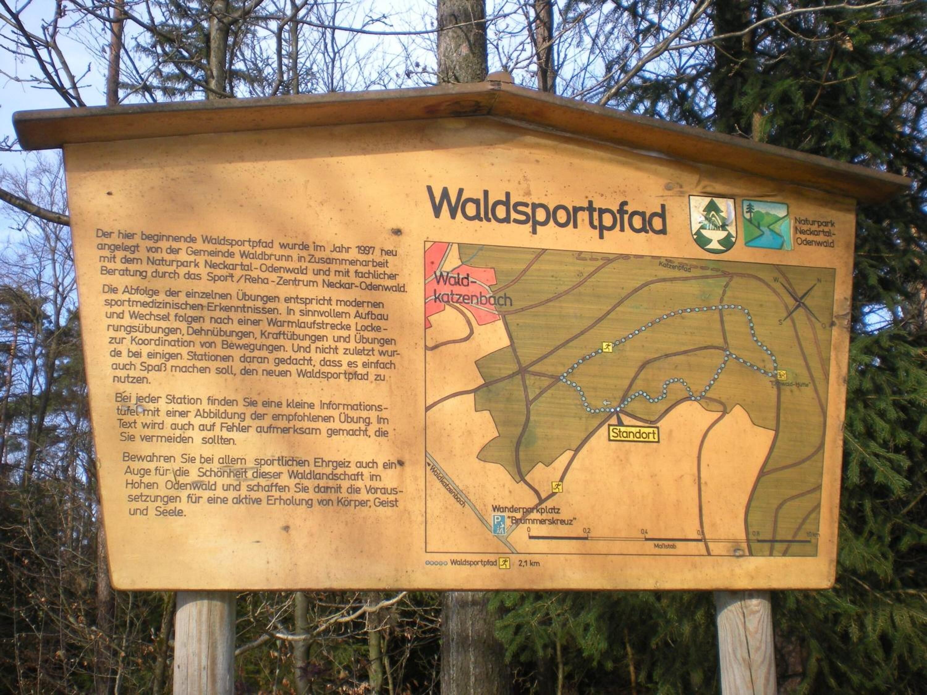 Um painel de madeira com um mapa e texto descrevendo uma trilha para caminhada.