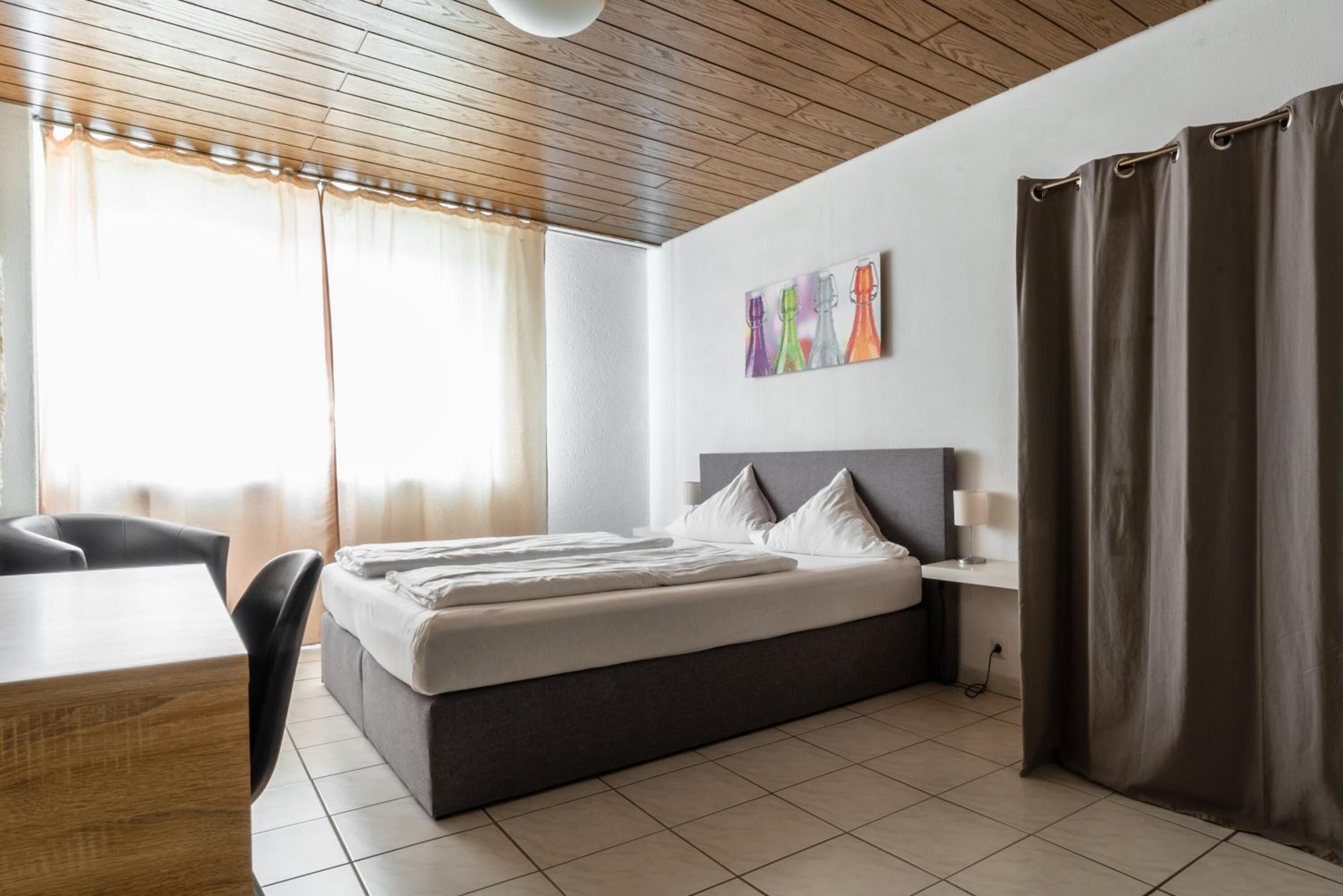 Une chambre d’hôtel moderne avec un grand lit, un bureau et une fenêtre avec des rideaux.