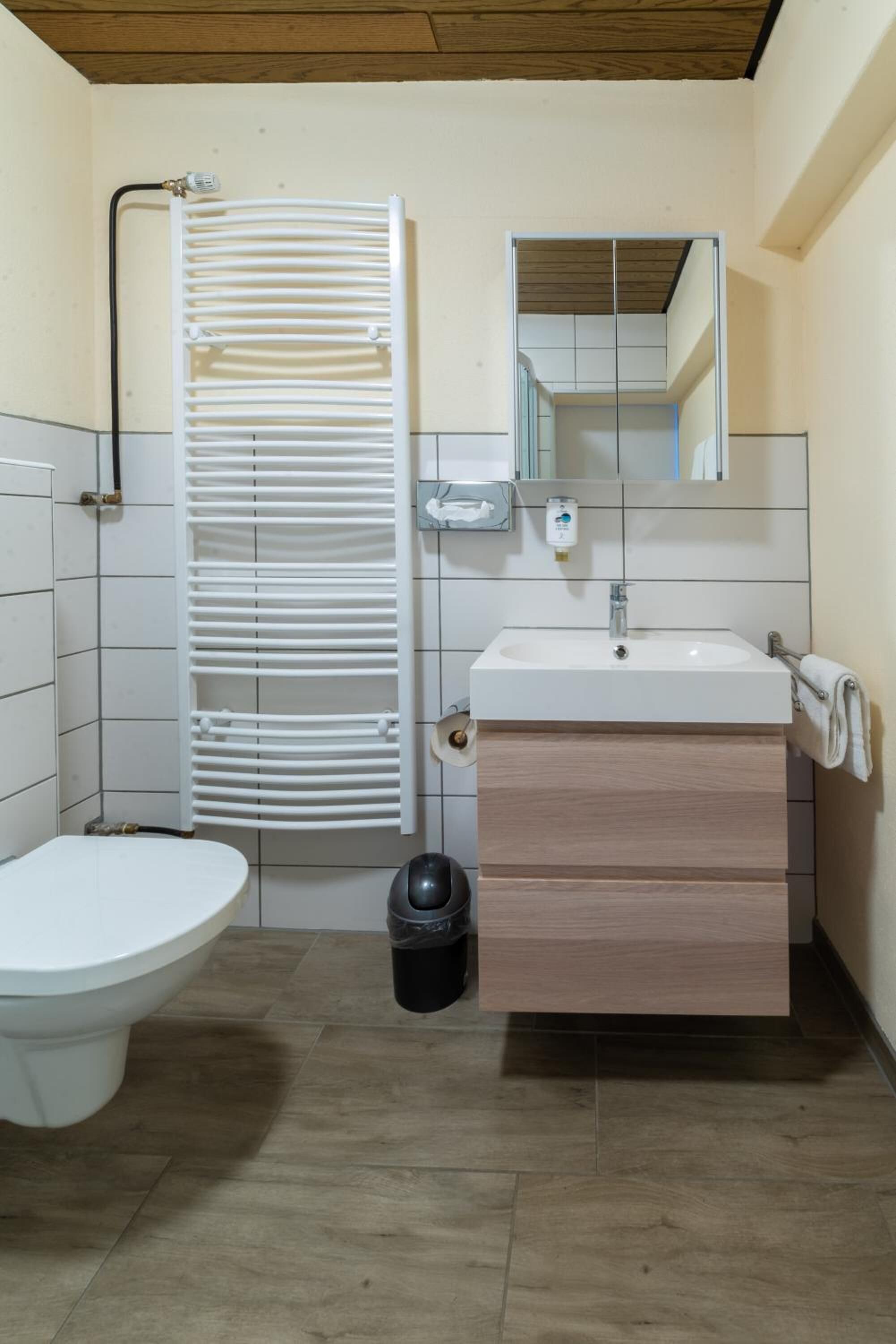A small bathroom with a toilet, sink, and white radiator.