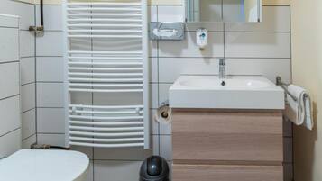 A small bathroom with a toilet, sink, and white radiator.