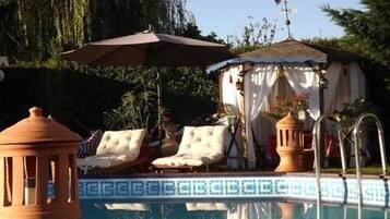 Alberca al aire libre, sombrillas en la alberca y camastros