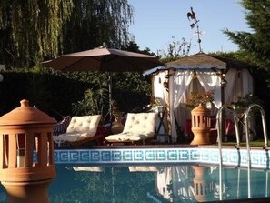 Een buitenzwembad, parasols bij het zwembad en ligstoelen