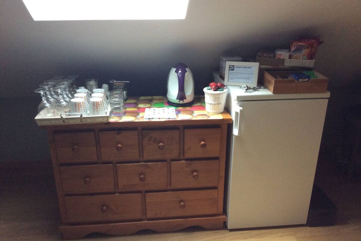 Una kitchenette con un mueble de madera, un refrigerador y diversos utensilios de cocina sobre la encimera.
