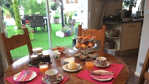 Une table de petit-déjeuner dressée avec divers aliments, notamment des viennoiseries, un saladier de fruits et des boissons.