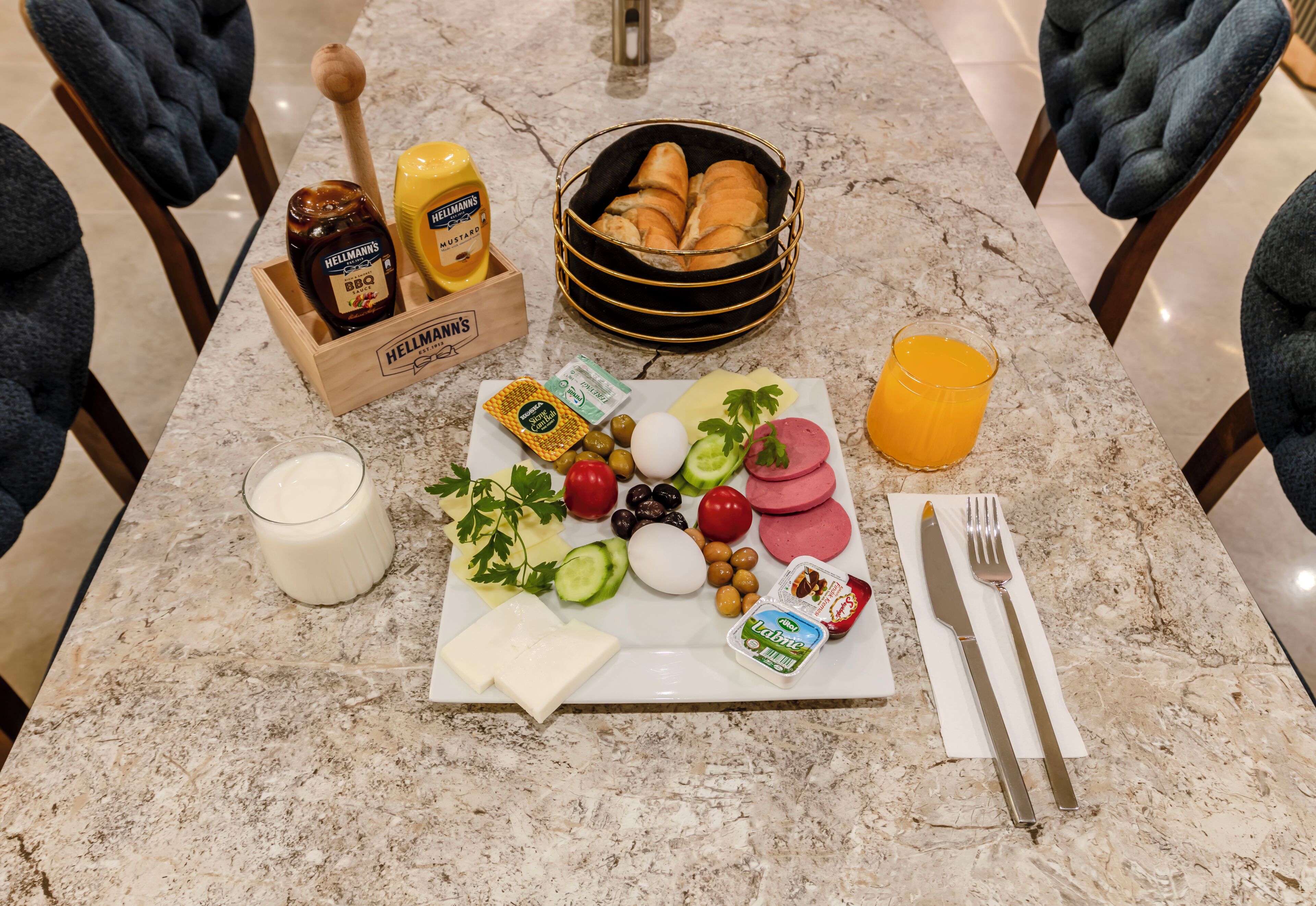 Ein Frühstückstisch mit Brot, Eiern, Käse und Obst auf einer Marmortafel.