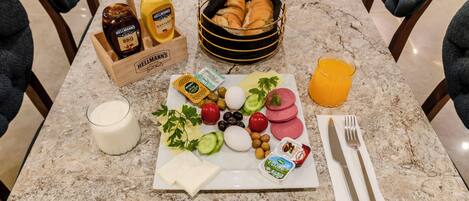 A breakfast setup with bread, eggs, cheese, and fruits on a marble table.