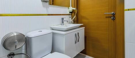 Un baño moderno con inodoro, lavamanos y espejo.