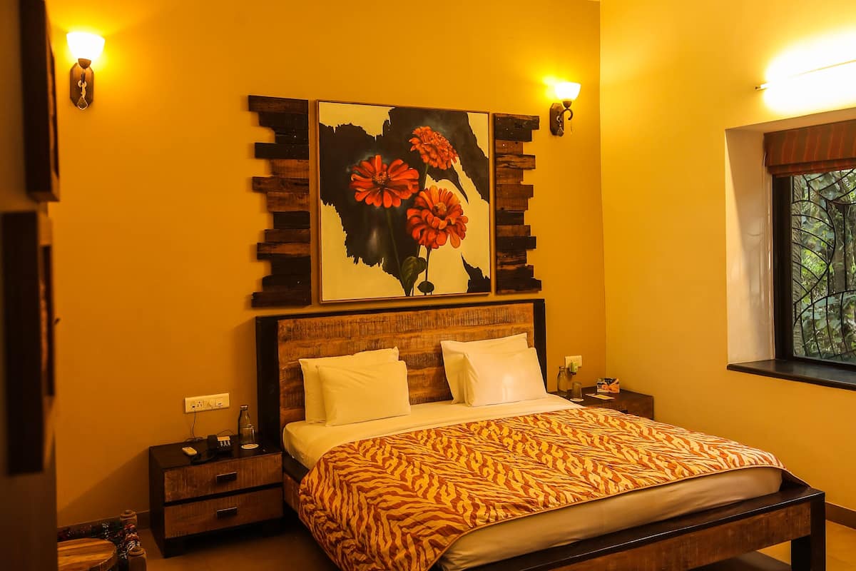 A bedroom with a bed, nightstands, a chair, a ceiling fan, and a window with a view of trees.
