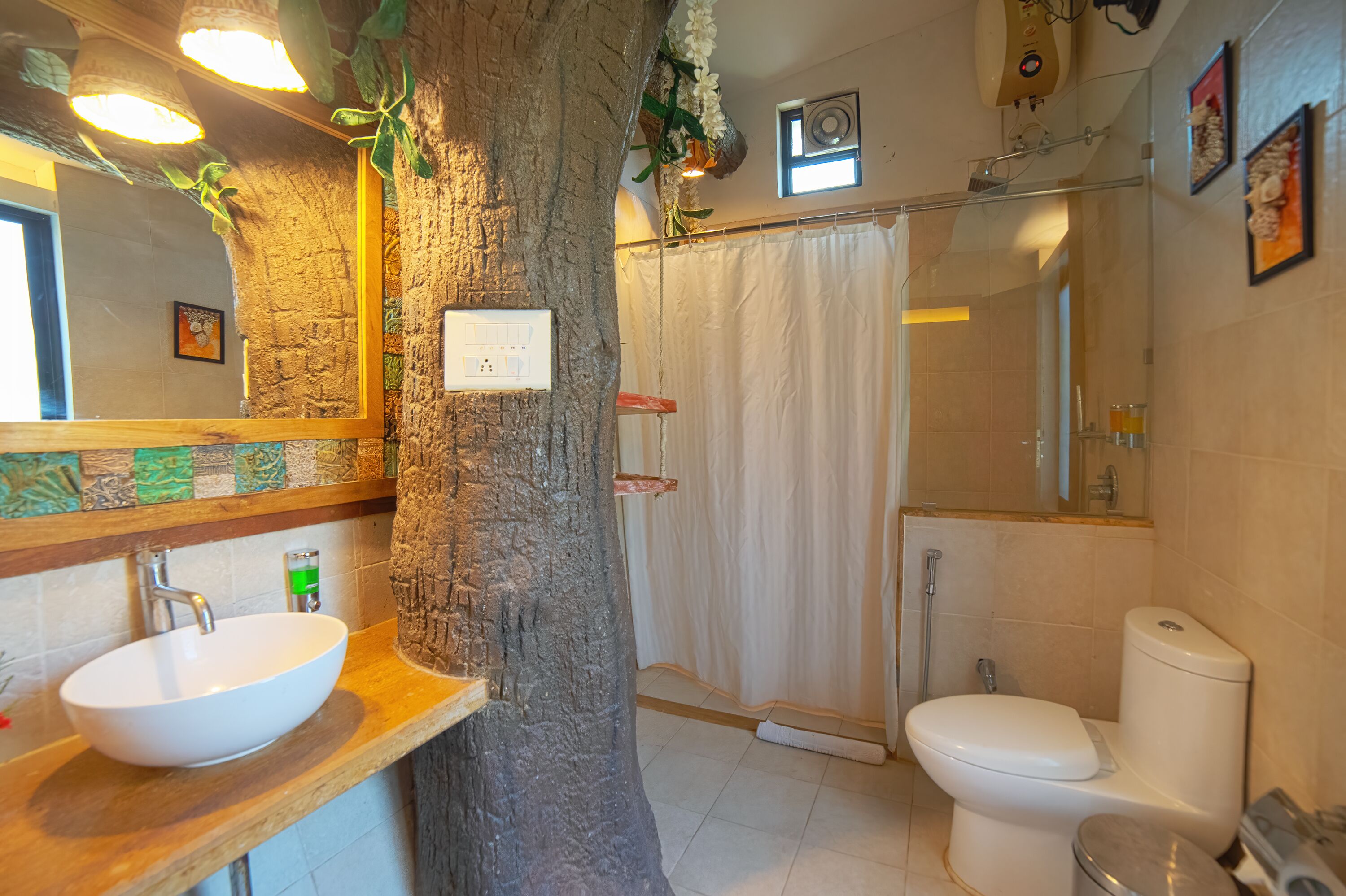 Une salle de bain avec un tronc d’arbre, un lavabo blanc, des toilettes et un rideau de douche.
