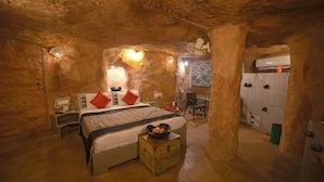 Una habitación que recuerda a una cueva, con una cama, una pequeña mesa con un cuenco y una silla.