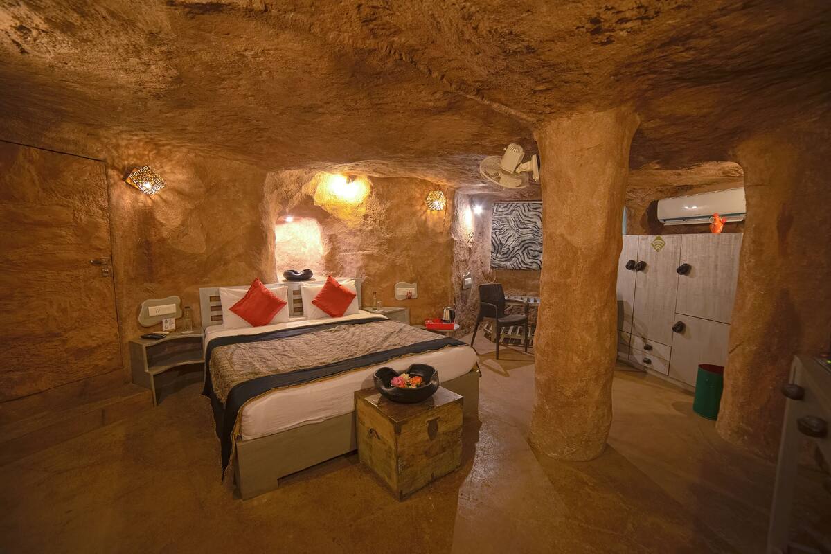 A cave-like room with a bed, a small table with a bowl, and a chair.