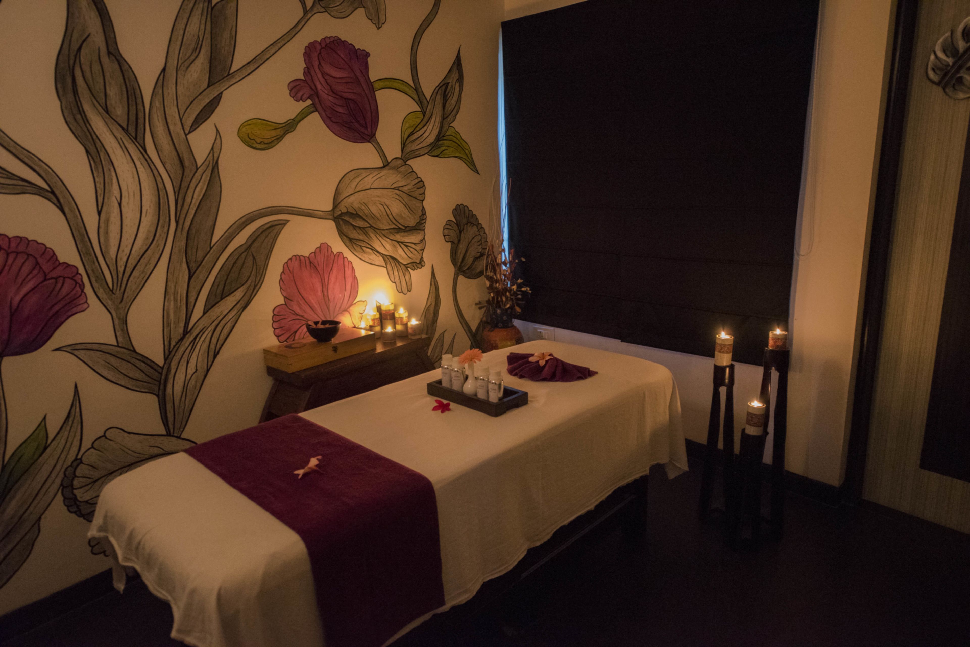A spa room with a massage table, candles, and a wall mural.